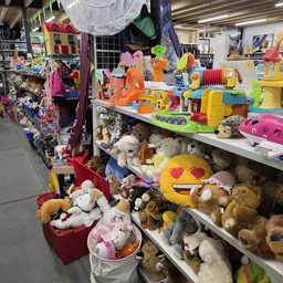 Uitgestalde speelgoed en knuffels op tafels en stellingen in de kringloopwinkel