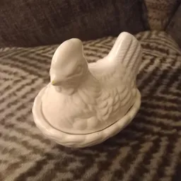 Witte keramische decoratie in de vorm van een vogel op een witte ondergrond