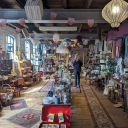 Ruim en gezellig interieur van kringloopwinkel met houten vloer, veel rekken met diverse tweedehands spullen, boeken, decorat