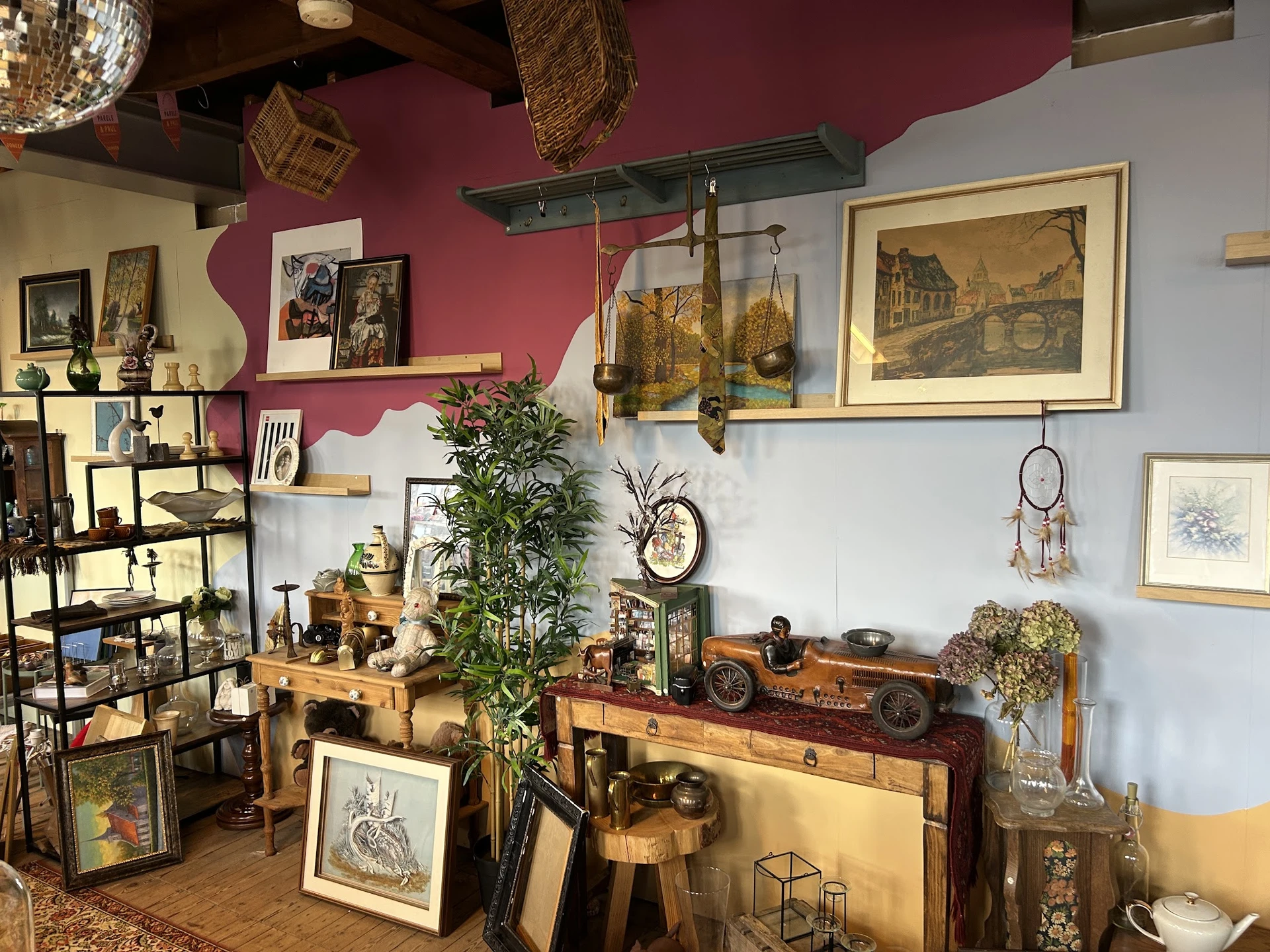 Uitgestalde antieke en vintage artikelen: schilderijen, planten, houten meubels, decoratie en kunstvoorwerpen in een kleurrij