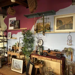 Uitgestalde antieke en vintage artikelen: schilderijen, planten, houten meubels, decoratie en kunstvoorwerpen in een kleurrij