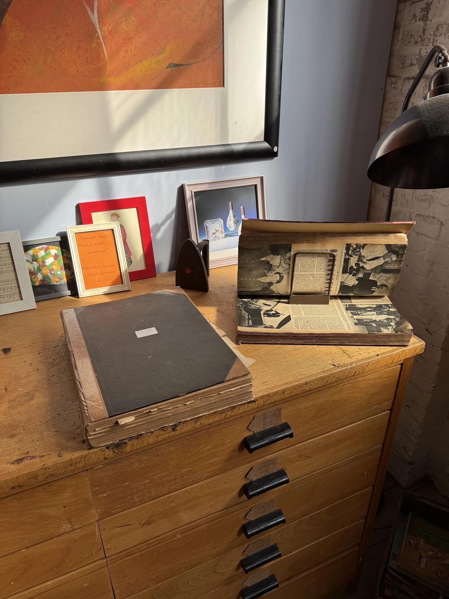 Houten bureau met vintage foto-albums en fotoboeken, plus enkele ingelijste foto's op de achtergrond