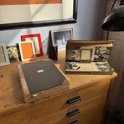 Houten bureau met vintage foto-albums en fotoboeken, plus enkele ingelijste foto's op de achtergrond