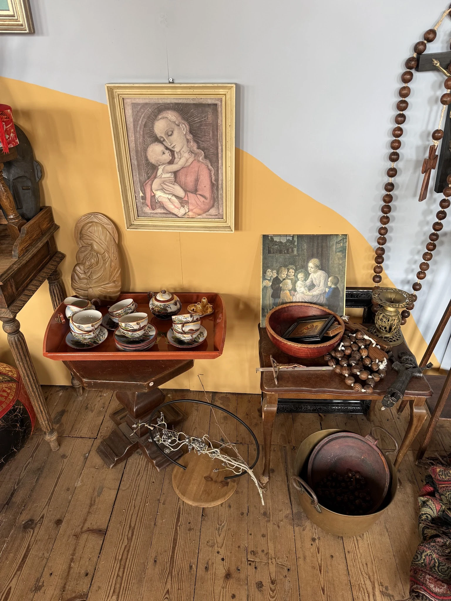 Uitgestalde antieke en vintage items: serviesgoed, beeldjes, schilderijen en decoratieve voorwerpen op houten meubels