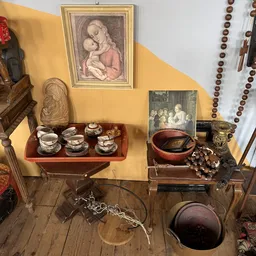 Uitgestalde antieke en vintage items: serviesgoed, beeldjes, schilderijen en decoratieve voorwerpen op houten meubels
