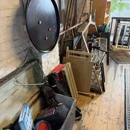Rommelig magazijn of opslagruimte met dozen, fietsen, vissen en andere spullen