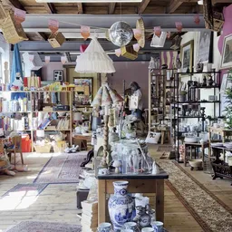 Overzicht van de winkelruimte met stellingen vol spullen, een centrale tafel met items en hangende decoraties aan het plafond