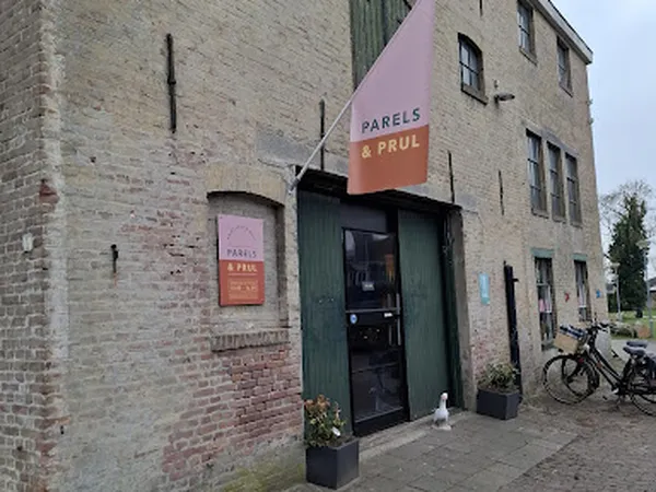 Voorgevel van kringloopwinkel Parels & Prul met groene deur en twee borden met winkelnaam