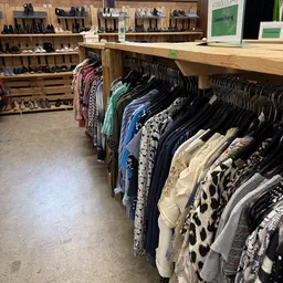 Rekken met tweedehands dameskleding op hangers in de kringloopwinkel