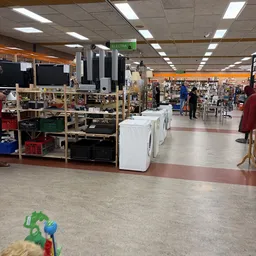 Winkelvloer met witgoedapparatuur, stellingen en klantenpaden in kringloopwinkel