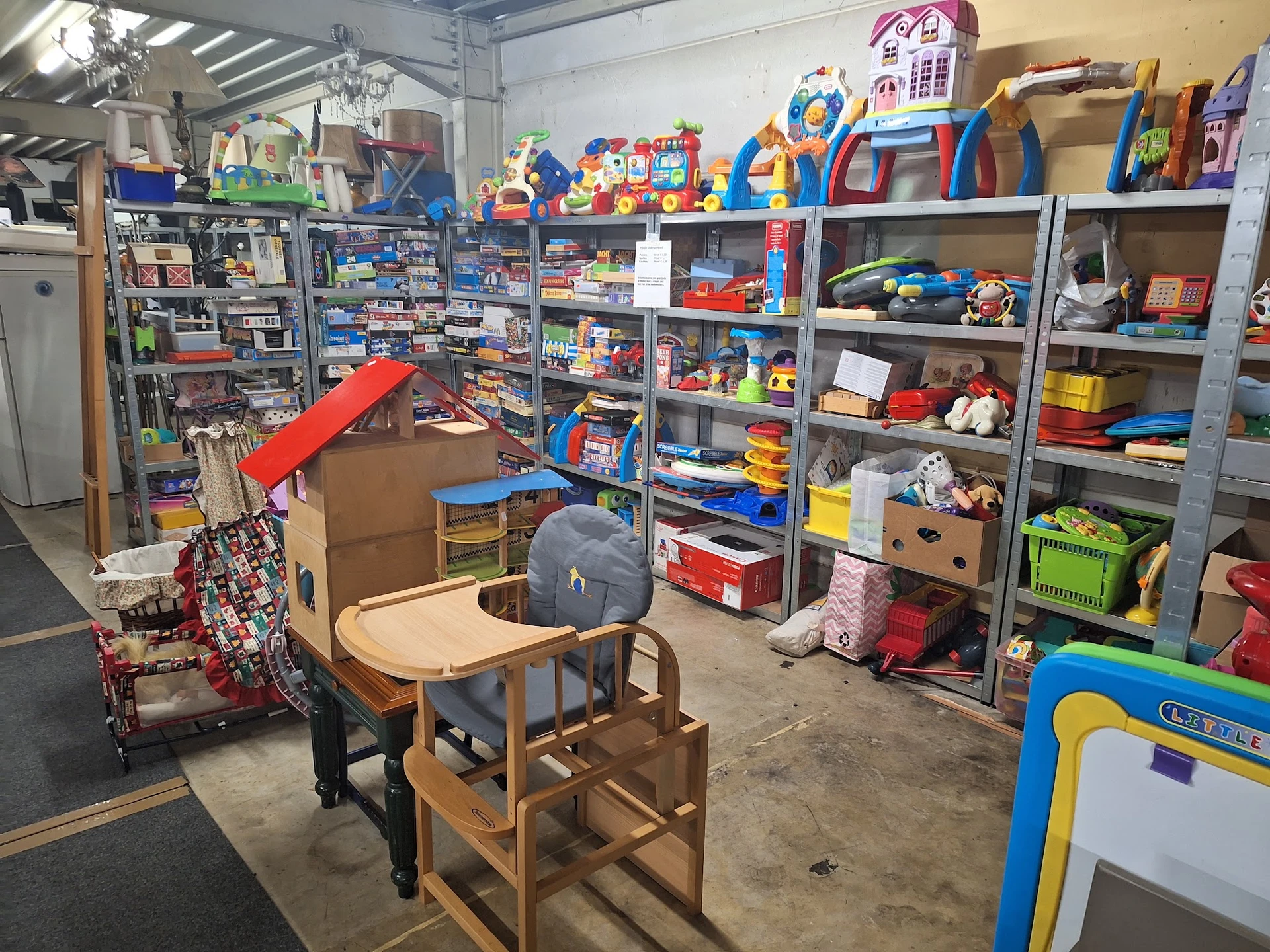 Winkelvloer met metalen stellingen vol speelgoed, kinderstoelen en diverse artikelen