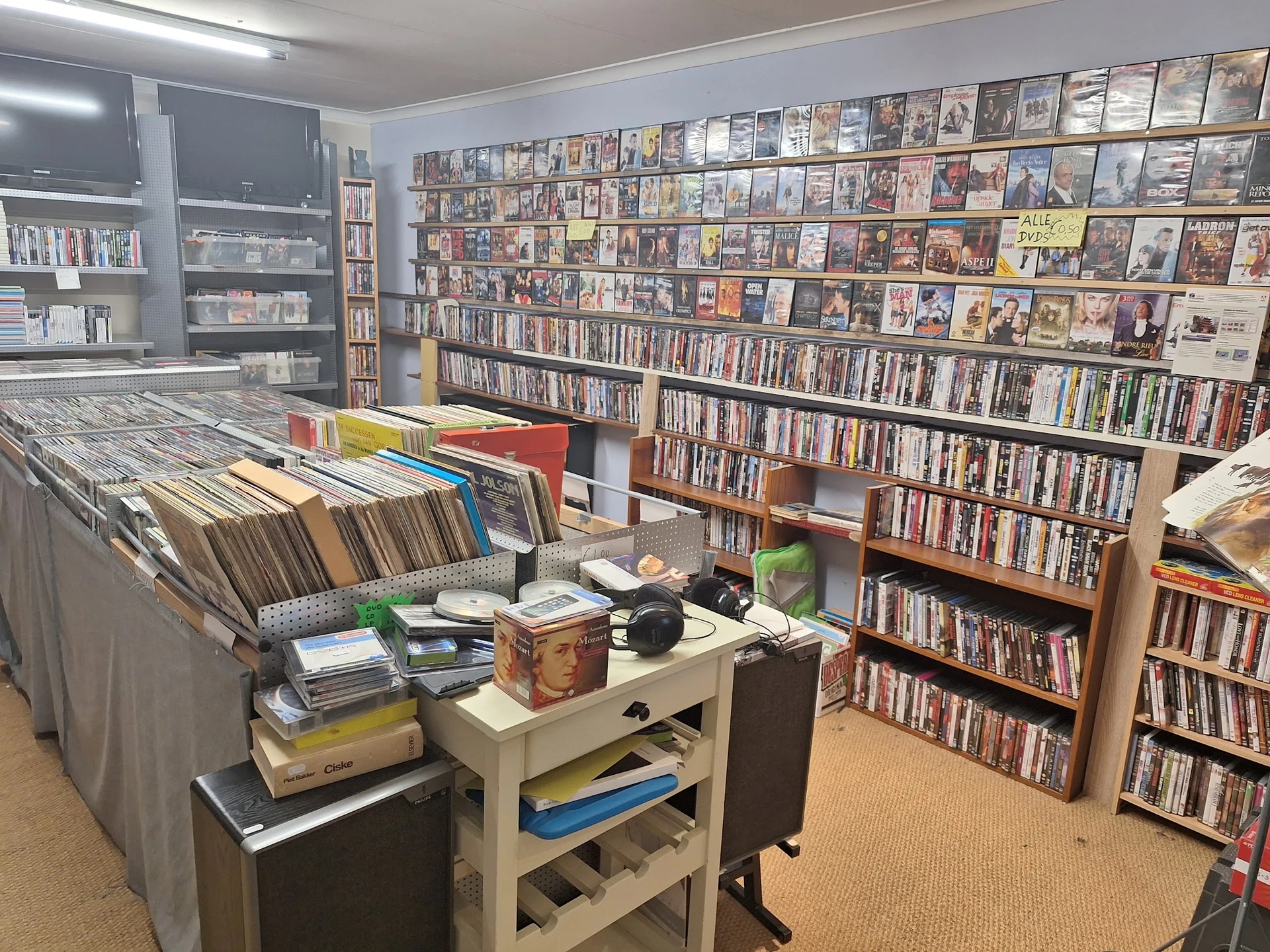 Winkelvloer met dvd- en cd-rekken, boekenkasten en een werktafel met diverse spullen
