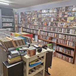 Winkelvloer met dvd- en cd-rekken, boekenkasten en een werktafel met diverse spullen