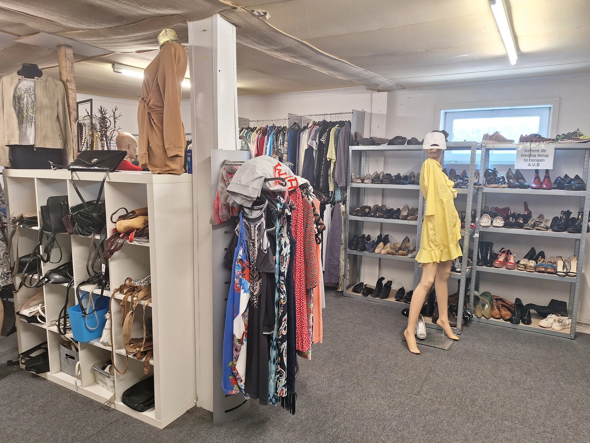 Overzicht van de winkelruimte met kledingrekken, mannequins met outfits, schoenenkastjes en stellingen met accessoires