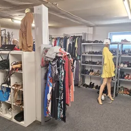 Overzicht van de winkelruimte met kledingrekken, mannequins met outfits, schoenenkastjes en stellingen met accessoires