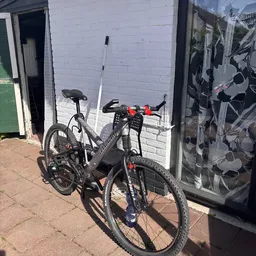 Twee mountainbikes tegen witte muur van gebouw, met rode en zwarte onderdelen