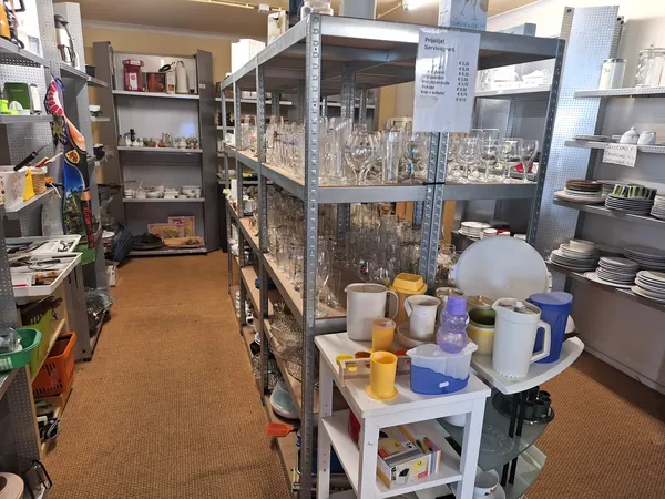 Interieur van kringloopwinkel met stellingen vol serviesgoed, glazen en huishoudartikelen