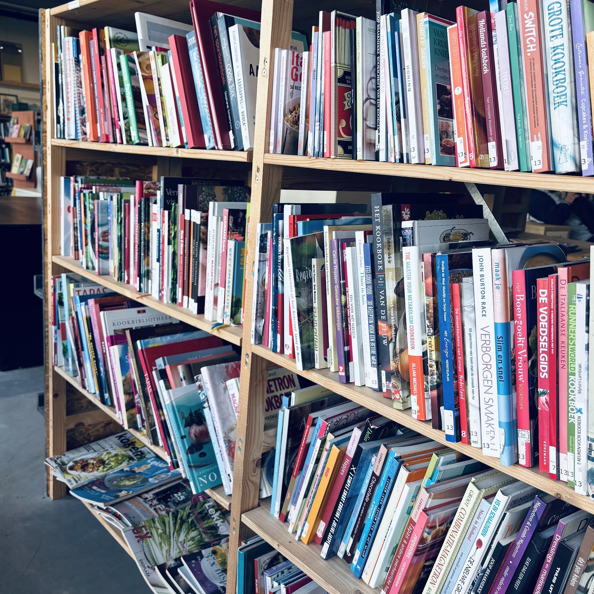 Houten stellingen gevuld met dvd's, blu-rays en cd's in verschillende kleuren en formaten