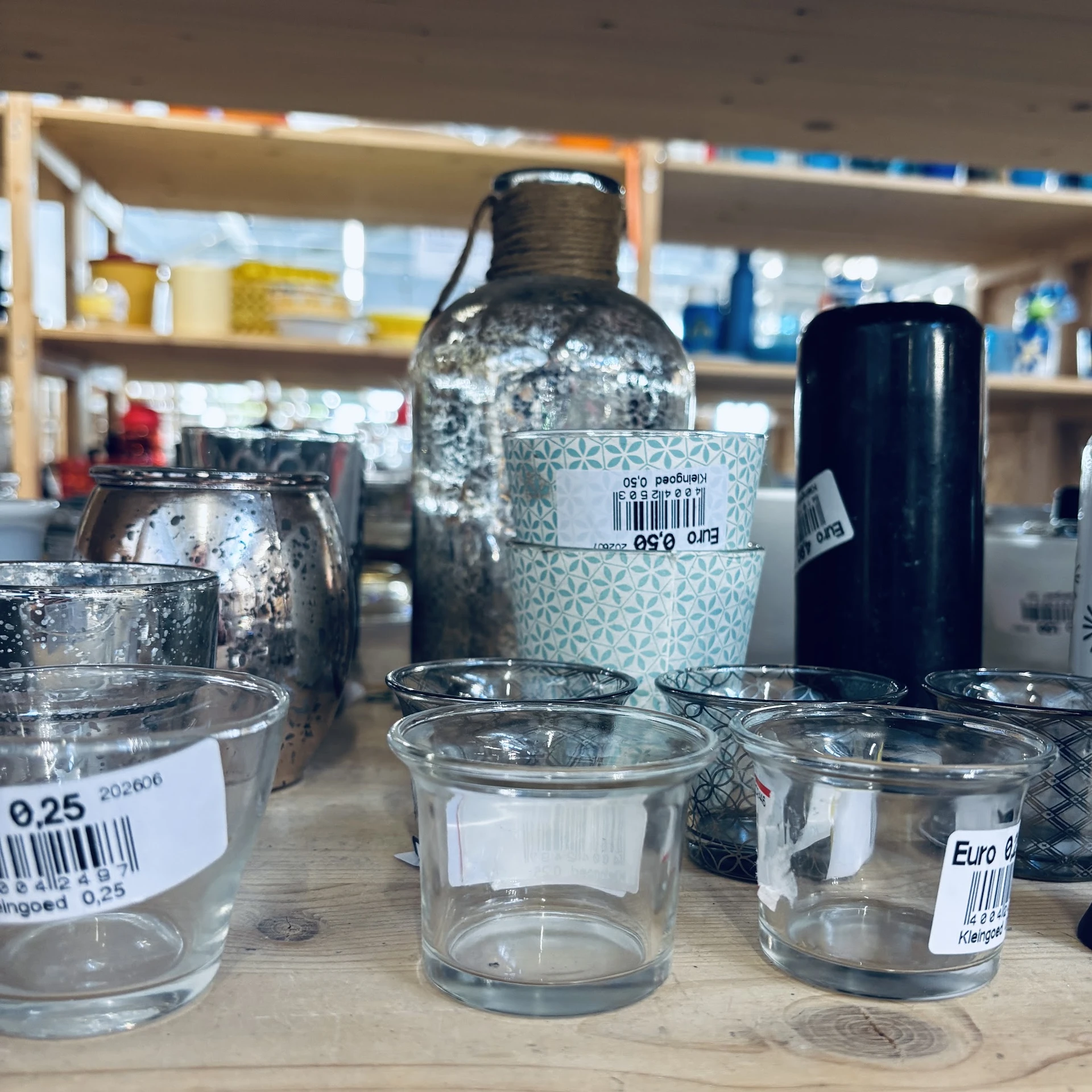 Glazen potjes en flessen met prijsstickers op een toonbank in een kringloopwinkel