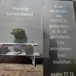 Condoleanceberichten op grijze panelen met bloempotten op een bankje