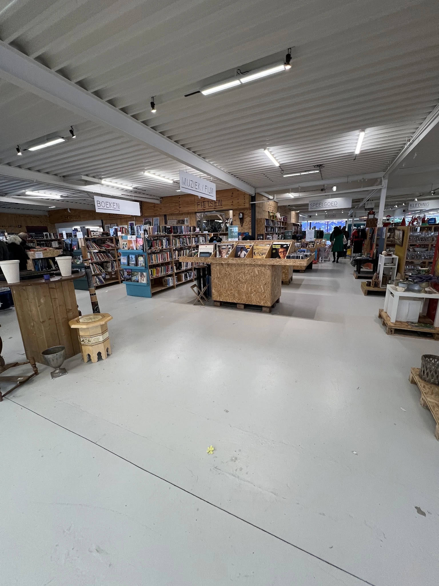 Ruime winkelhal met boekenkasten, houten display-tafels en diverse tweedehands artikelen
