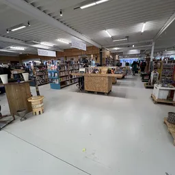 Ruime winkelhal met boekenkasten, houten display-tafels en diverse tweedehands artikelen
