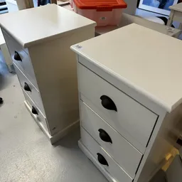 Twee witte nachtkastjes met zwarte handgrepen in de winkel