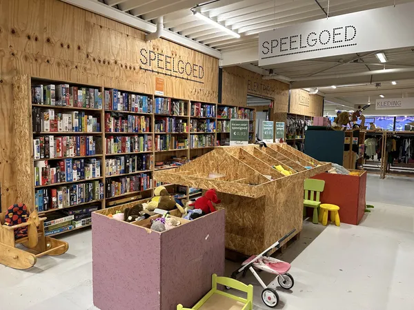 Speelgoedafdeling met boekenkast, speelgoed in grote dozen en kinderspeelgoed op de winkelvloer