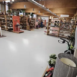 Winkelvloer van kringloopwinkel met stellingen en display-kasten in de achtergrond, voorgrond met plantenpot en elektrische f