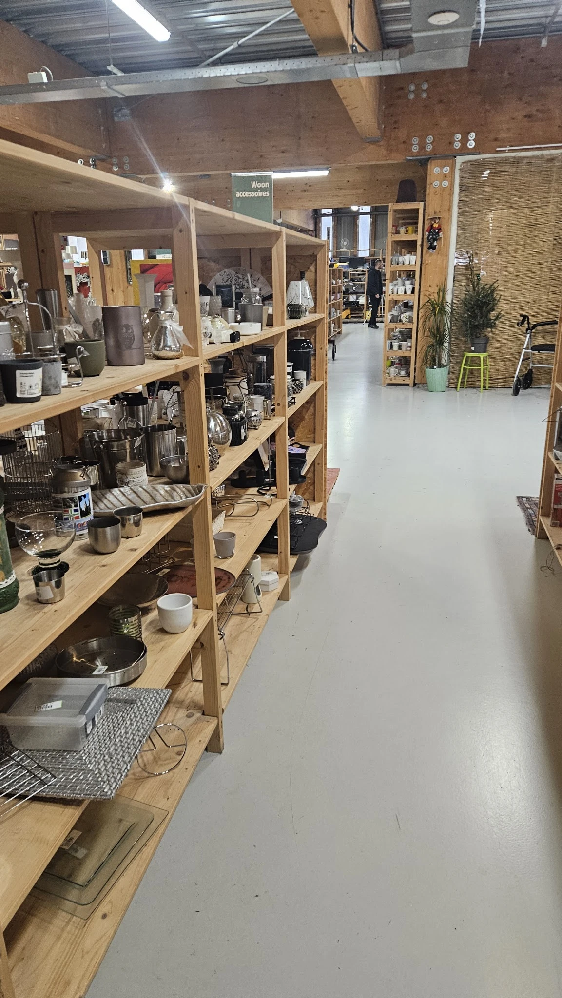 Houten stellingen met huishoudelijke artikelen en decoratiespullen in een kringloopwinkel
