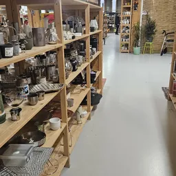Houten stellingen met huishoudelijke artikelen en decoratiespullen in een kringloopwinkel