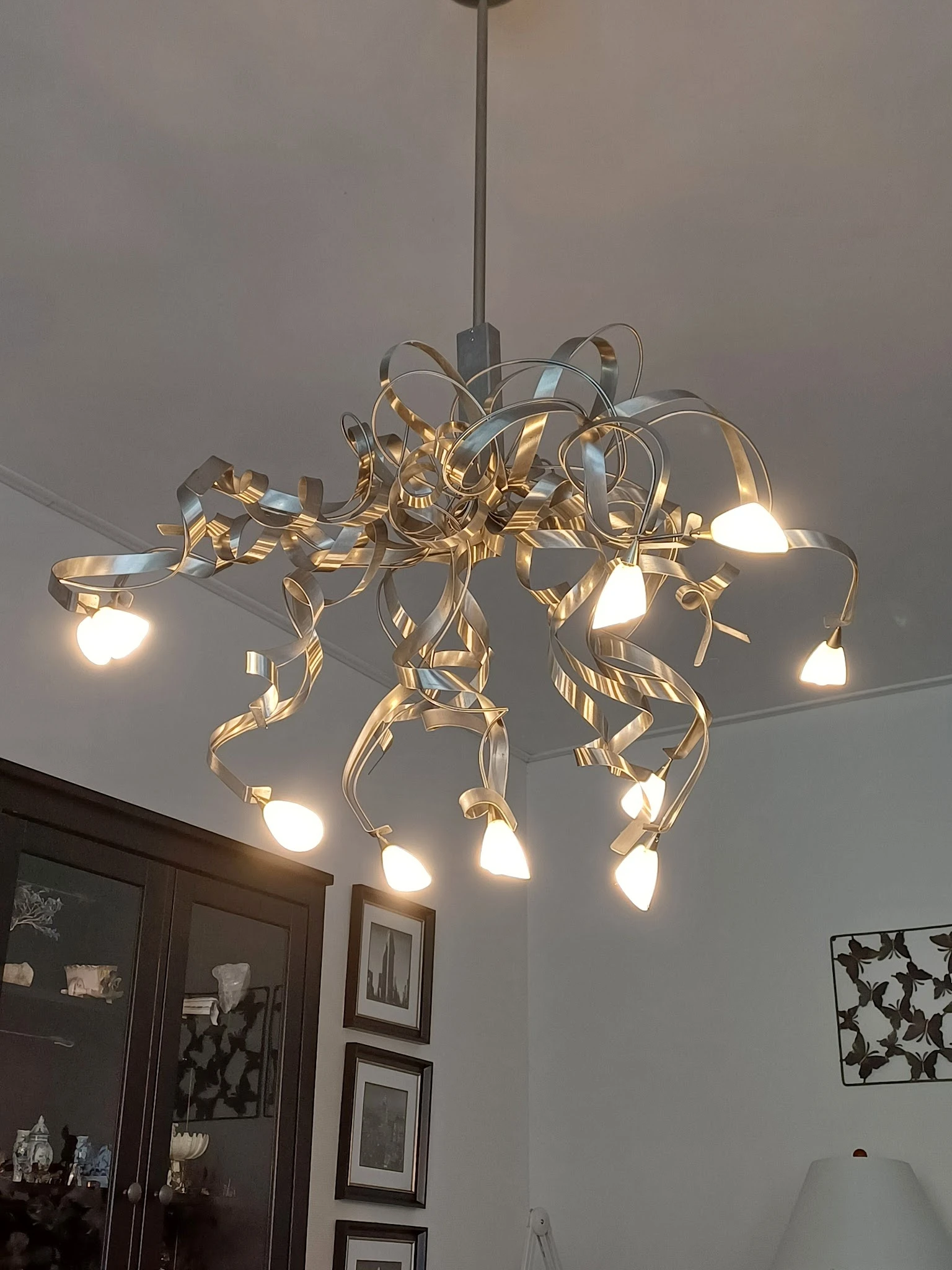 Goudkleurige hanglamp met meerdere armen en glazen kappen aan het plafond