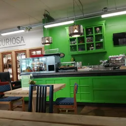 Groene lunchroom-inrichting met toonbank, zithoeken en uitgestalde spullen in kringloopwinkel