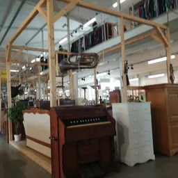 Winkelvloer met houten stellingen, piano, meubels en diverse artikelen in kringloopwinkel