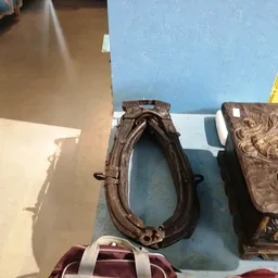 Tweedehands lederen tassen en decoratieve objecten op een blauwe werktafel