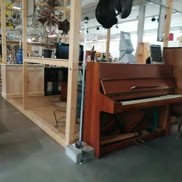 Winkelinterieur met bruine piano en houten stellingen met spullen