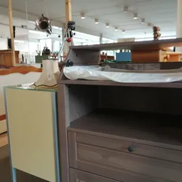 Tweedehands meubels en huisraad uitgestald in een kringloopwinkel, waaronder kasten en laden.