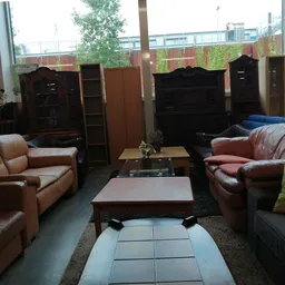 Winkelvloer met bruinleren banken, salontafels en houten kasten in een kringloopwinkel