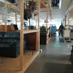 Ruim interieur van kringloopwinkel met houten scheidingswanden, zithoeken, meubels en stellingen