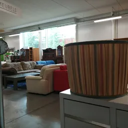 Winkelvloer met meubels, waaronder een gestreepte fauteuil op voorgrond en divans op achtergrond, kasten en accessoires