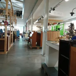 Winkelruimte met houten stellingen, displaykasten en artikelen langs de zijkanten, heldere verlichting en betonnen vloer