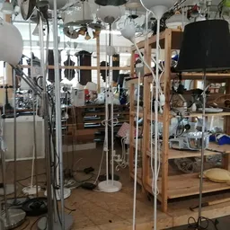 Winkelvloer met houten stellingen, vloerlamp en diverse spullen in een kringloopwinkel