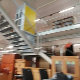 Wazig zicht op winkelvloer met stellingen, kasten en een persoon met rode jas in het interieur
