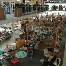 Overzicht van de winkelvloer met houten stellingen, speelgoed, boeken en diverse tweedehandsartikelen