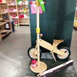 Houten kinderfiets en houten speelgoed, waaronder een speelmobiel met gekleurde ballen en een houten paard