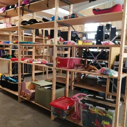 Houten stellingkast met diverse tweedehands spullen, kleding en huishoudartikelen in een kringloopwinkel
