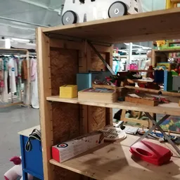 Houten speelgoedkast met verschillende speelgoed, poppen en accessoires uitgestald op meerdere niveaus
