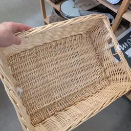 Lichtbruine rieten mand met handvaten, vastgehouden door een hand