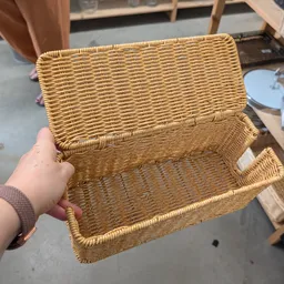 Geopende rieten mand in natuurlijke kleur, gehouden in hand