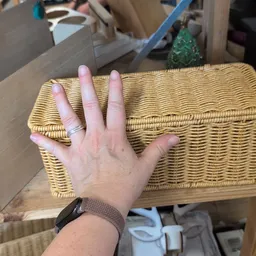 Hand met ring op gele rieten mand